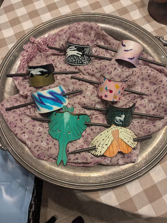 A bowl of hand-painted leather hair barrettes, including a luna moth design